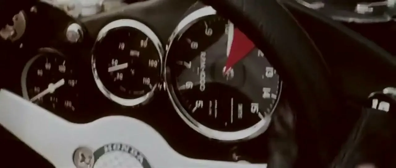 A close-up shot of a vintage car's dashboard, showing the speedometer and tachometer with the Honda logo visible on the steering wheel.