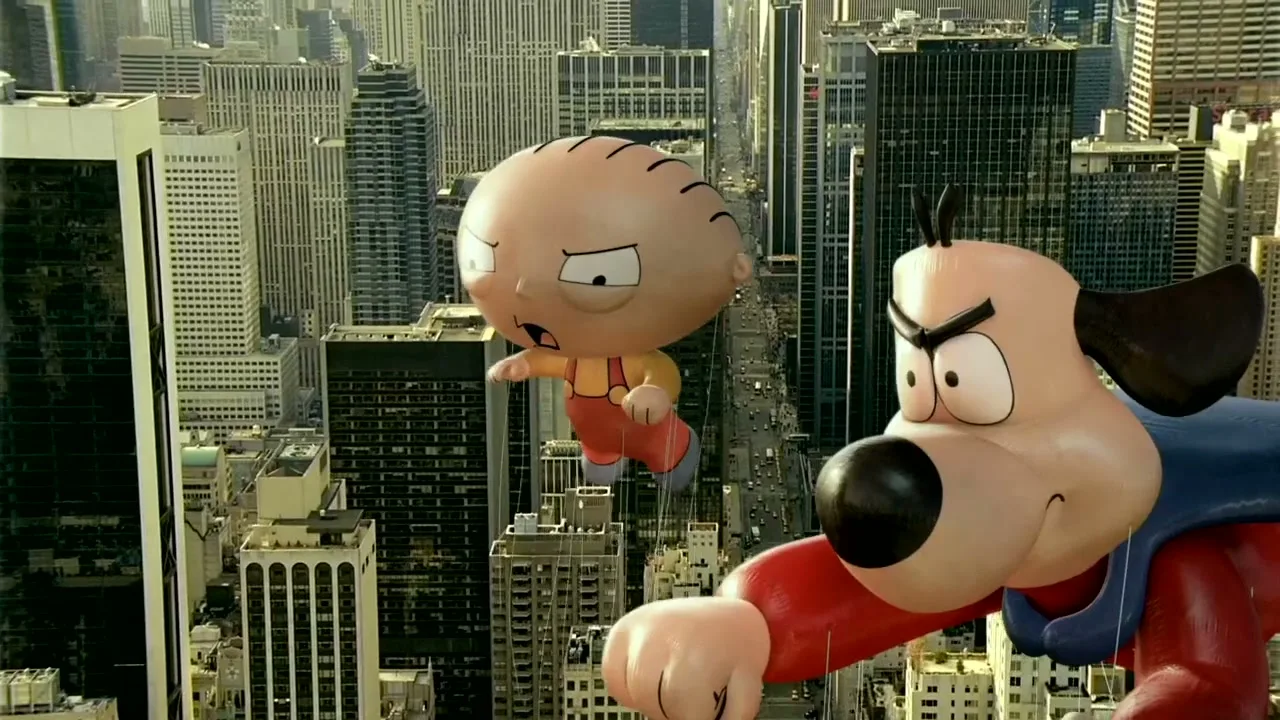 Stewie Griffin and Brian the dog balloons from Family Guy float above a city street during a parade.