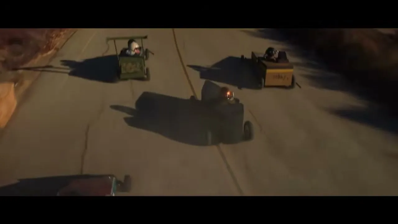 Three children race soapbox derby cars down a winding road during golden hour.