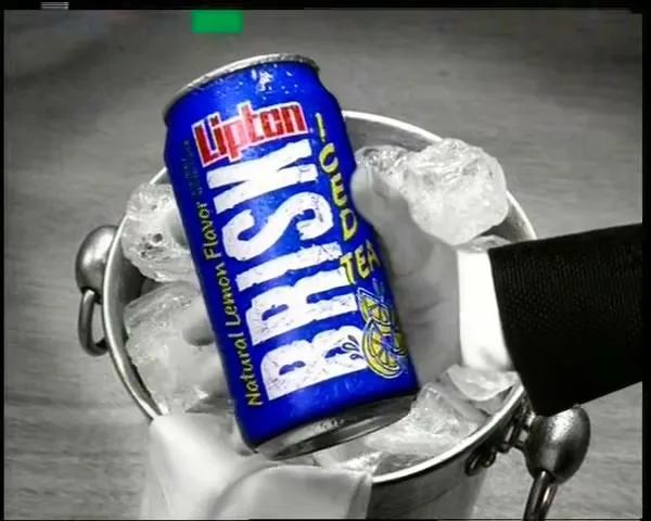 A gloved hand in a suit jacket reaches into an ice bucket to grab a blue can of Lipton Brisk Iced Tea.