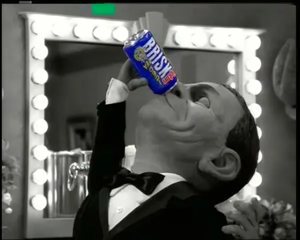 A stop-motion puppet of Frank Sinatra, in black and white, drinks a colorful can of Brisk iced tea in a dressing room.