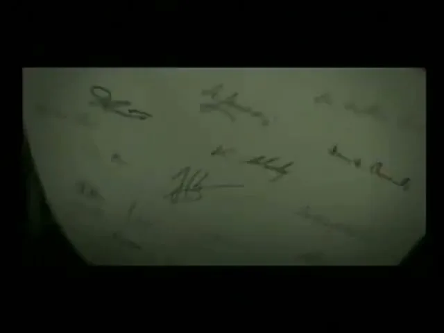 A bullet flies through a dark, confined space, then through a piece of paper covered in signatures, continuing its path.