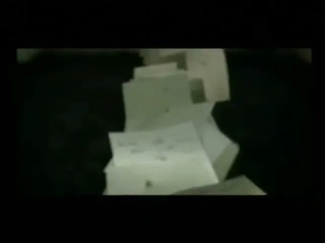 A stack of white papers with handwritten notes on them falls and scatters in a dark, confined space, suggesting a loss of information or freedom.