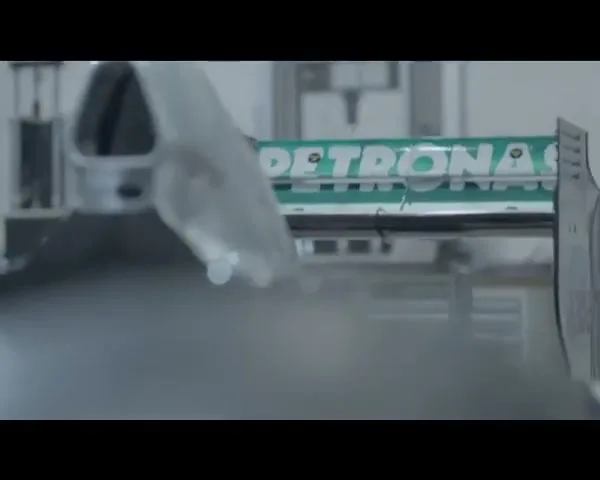 A close-up shot of a Petronas branded race car wing being worked on in a clean, industrial setting.