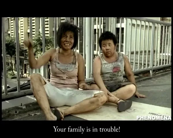 Two disheveled, dirty people, a woman and a child, sit on a concrete overpass, looking distressed as the woman gestures with her hand.