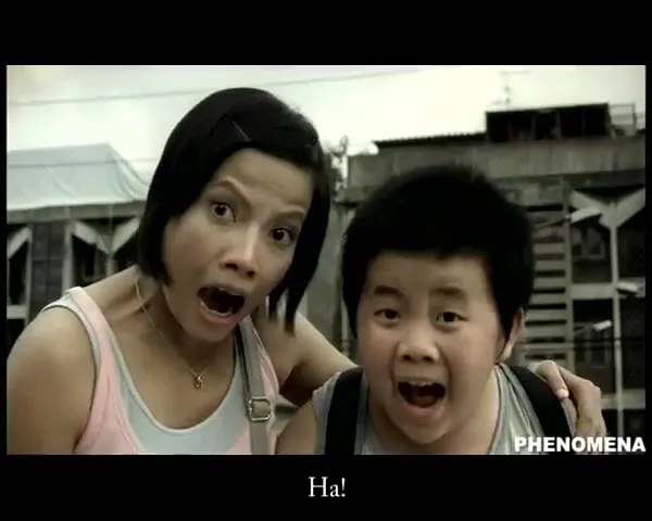 A woman and a boy look shocked and scream, with a blurry urban background behind them.