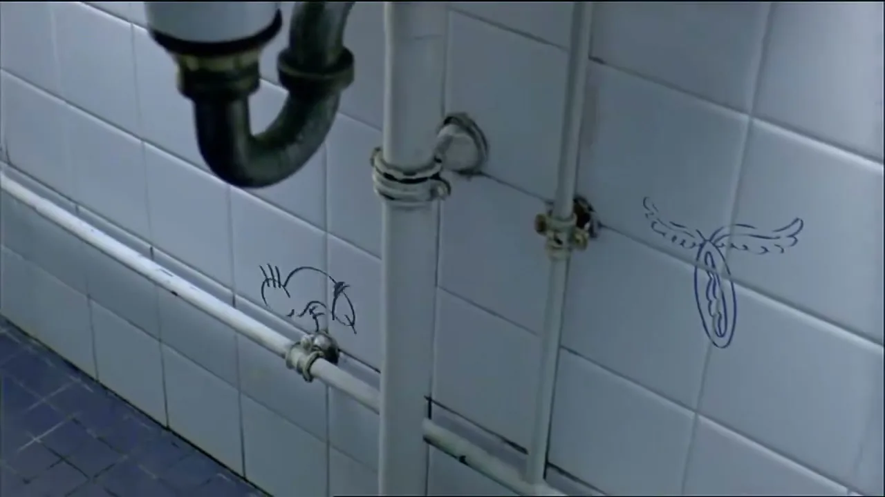 A close-up shot of a white tiled wall with pipes, as animated graffiti drawings of sexual organs appear and disappear, in a public restroom.