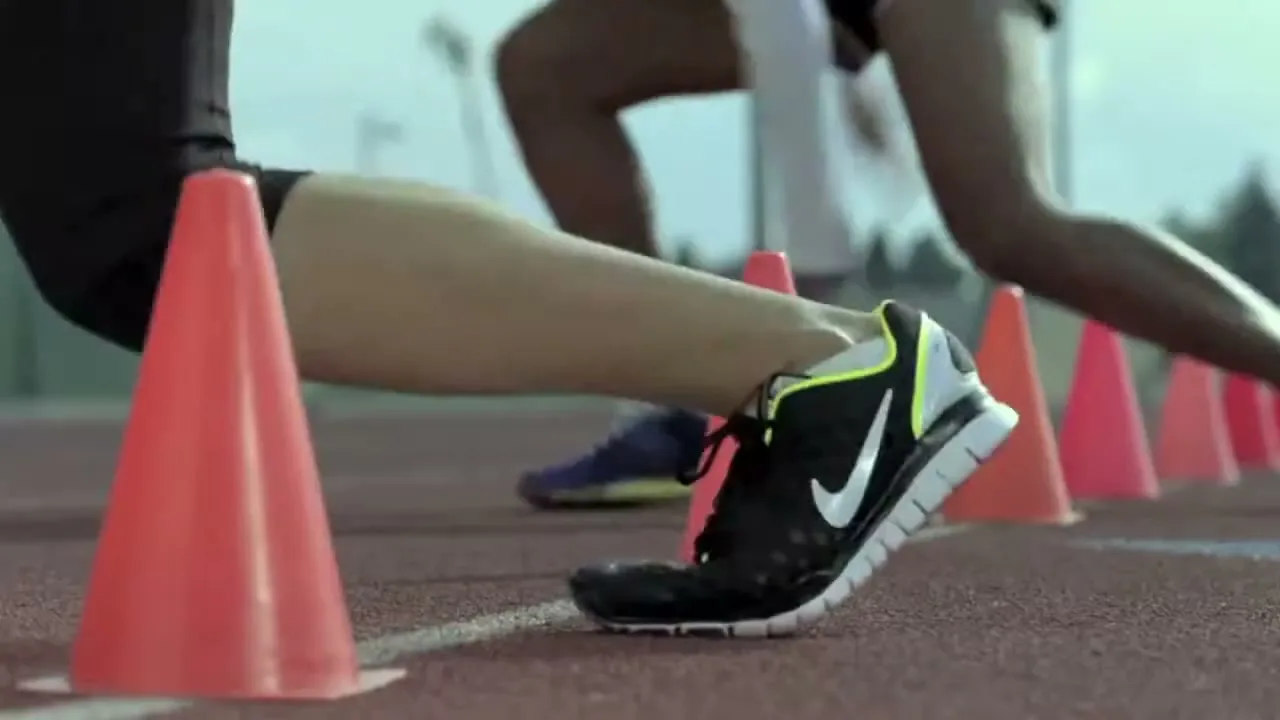 A runner's legs and feet are seen in a medium shot as they run past a line of orange cones on a track.