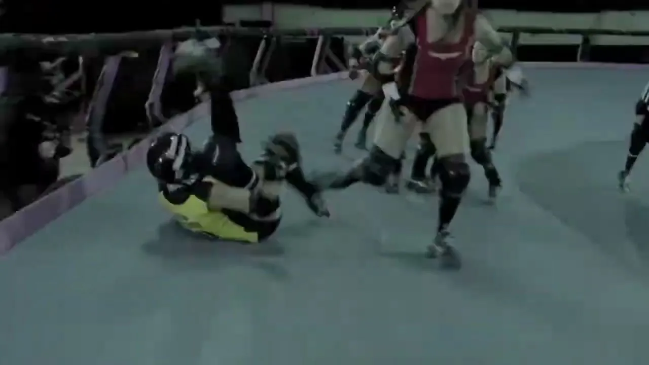 A female roller derby player in a yellow jersey falls to the ground during a match on a roller derby track.