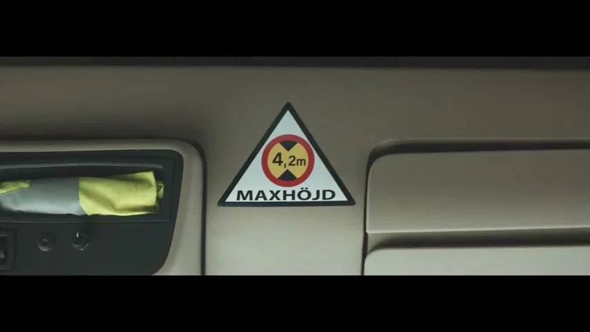 A close-up shot of a "MAXHÖJD 4,2m" sign inside a truck cabin, with a yellow cloth visible on the left.