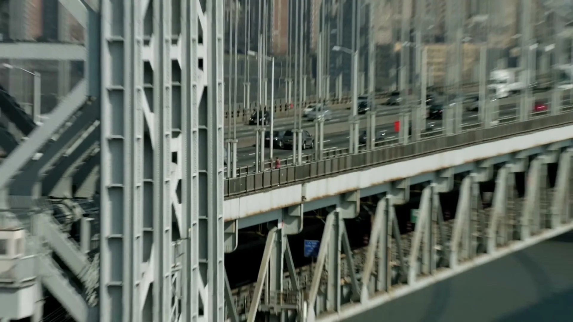 A young woman in athletic wear runs across a bridge with a city skyline in the background on a clear day.