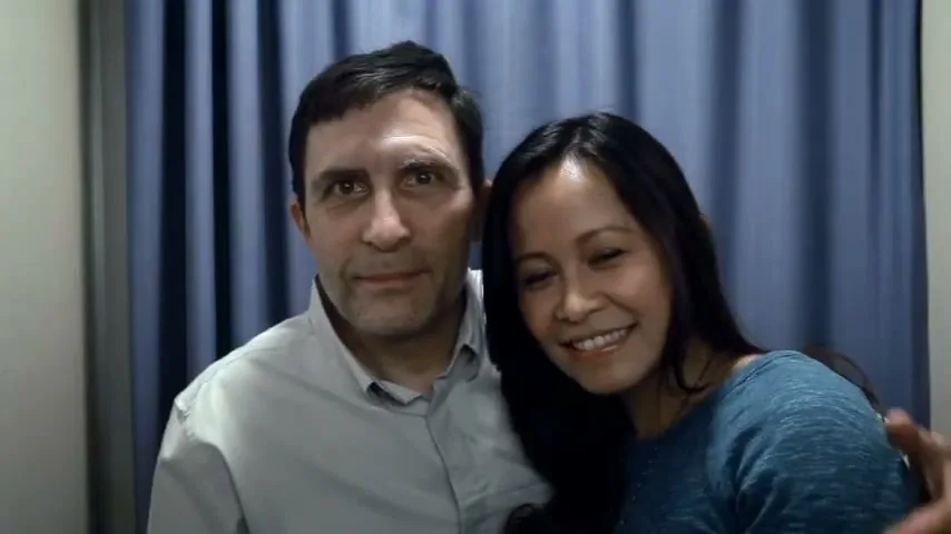 A man and a woman pose for a photo, smiling at the camera in a photo booth.