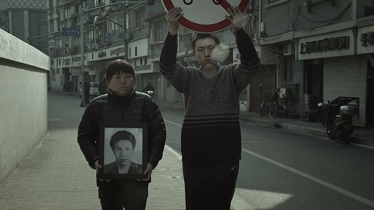 Two men walk down a city street, one holding a framed photo and the other a "no smoking" sign, as smoke billows from his mouth.