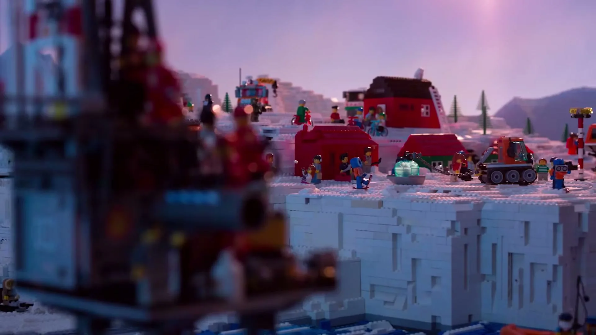 A wide shot of a Lego Arctic landscape shows various Lego figures and vehicles on snowy terrain, with a large drilling rig in the foreground.