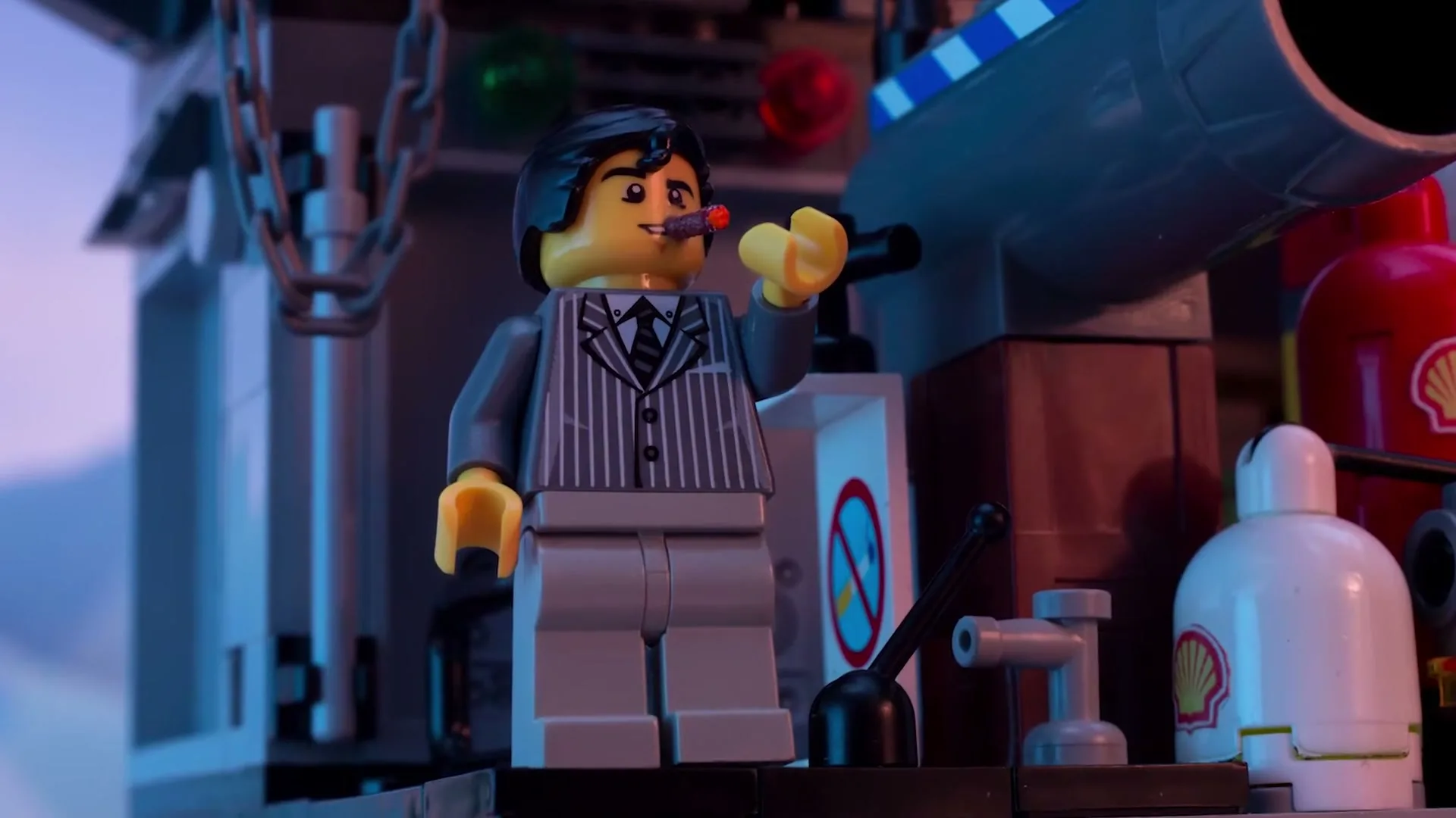 A Lego man in a pinstripe suit smokes a cigar, standing next to a large cannon and Shell-branded oil barrels.
