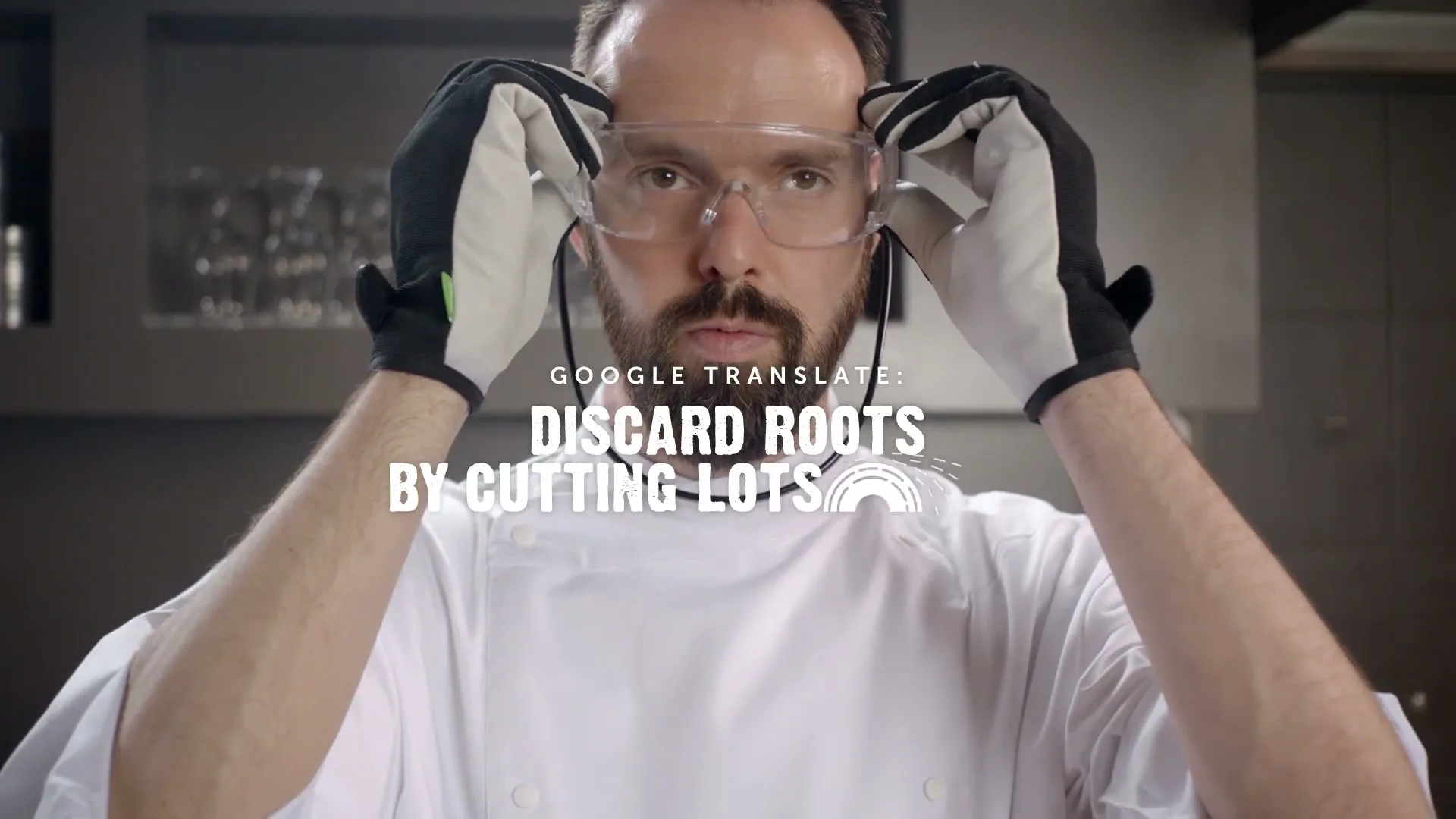 A male chef in a white jacket and black and white gloves puts on safety glasses in a kitchen, with text overlaying the scene.