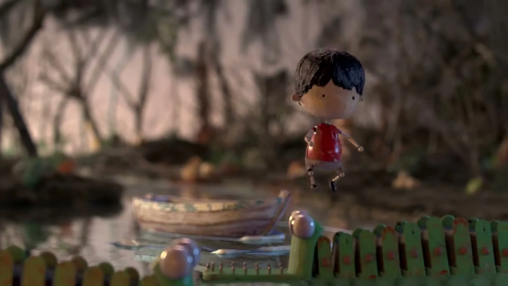 A stop-motion animated boy in a red shirt floats in a small boat on dark water, then jumps out as green, crocodile-like creatures emerge from the water in a swampy forest.