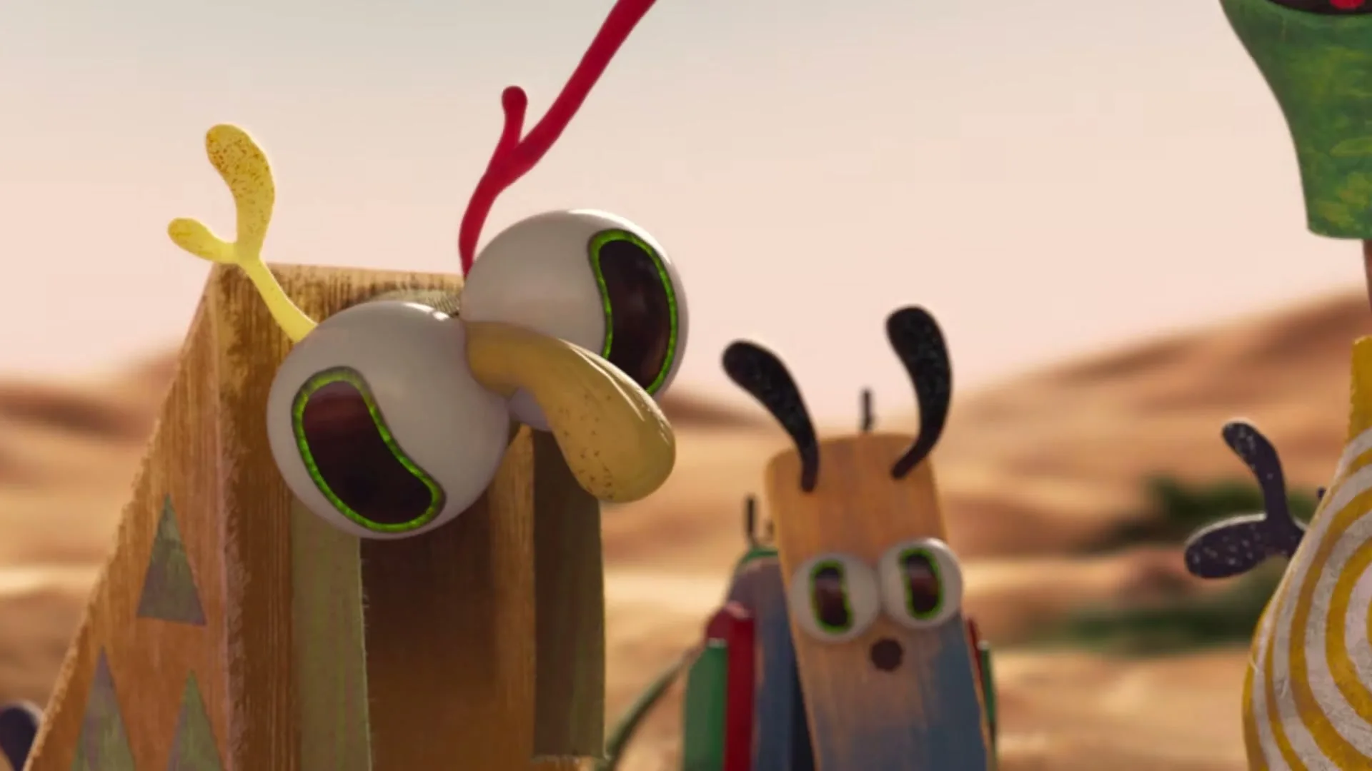 A stop-motion animated creature with large eyes and a yellow nose looks around in a desert-like landscape.