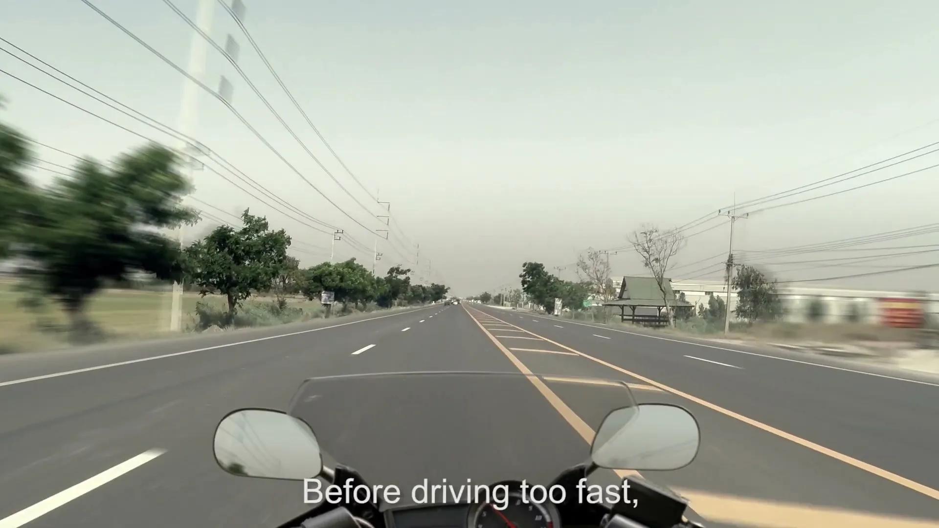 A first-person POV shot from a motorcycle speeding down a rural highway with power lines and trees on either side.