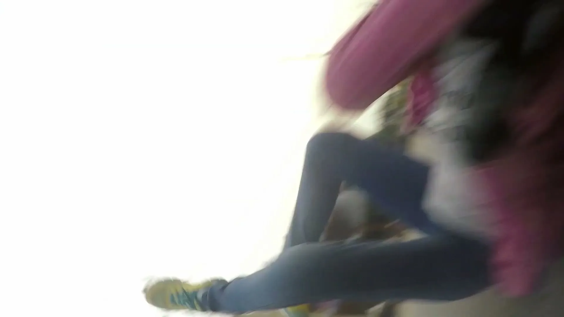 A person in a pink top and blue jeans is seen from a low angle, falling rapidly with motion blur against a bright white background.