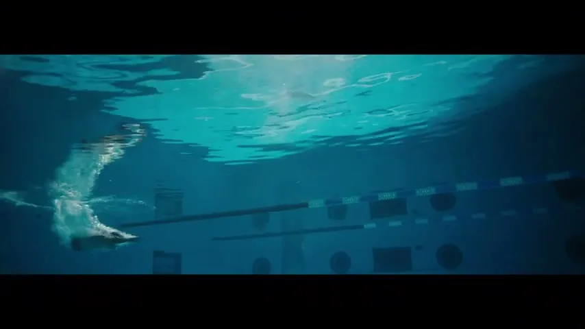 An underwater shot of a swimmer with prosthetic legs, swimming in a pool, with text overlay.