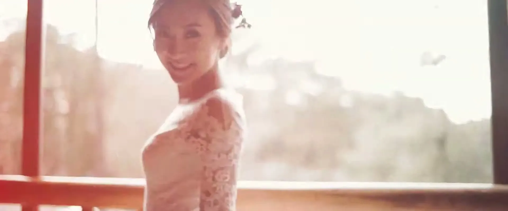 A beautiful bride in a white lace wedding dress and veil smiles, holding a bouquet of flowers, as she walks outdoors on her wedding day.