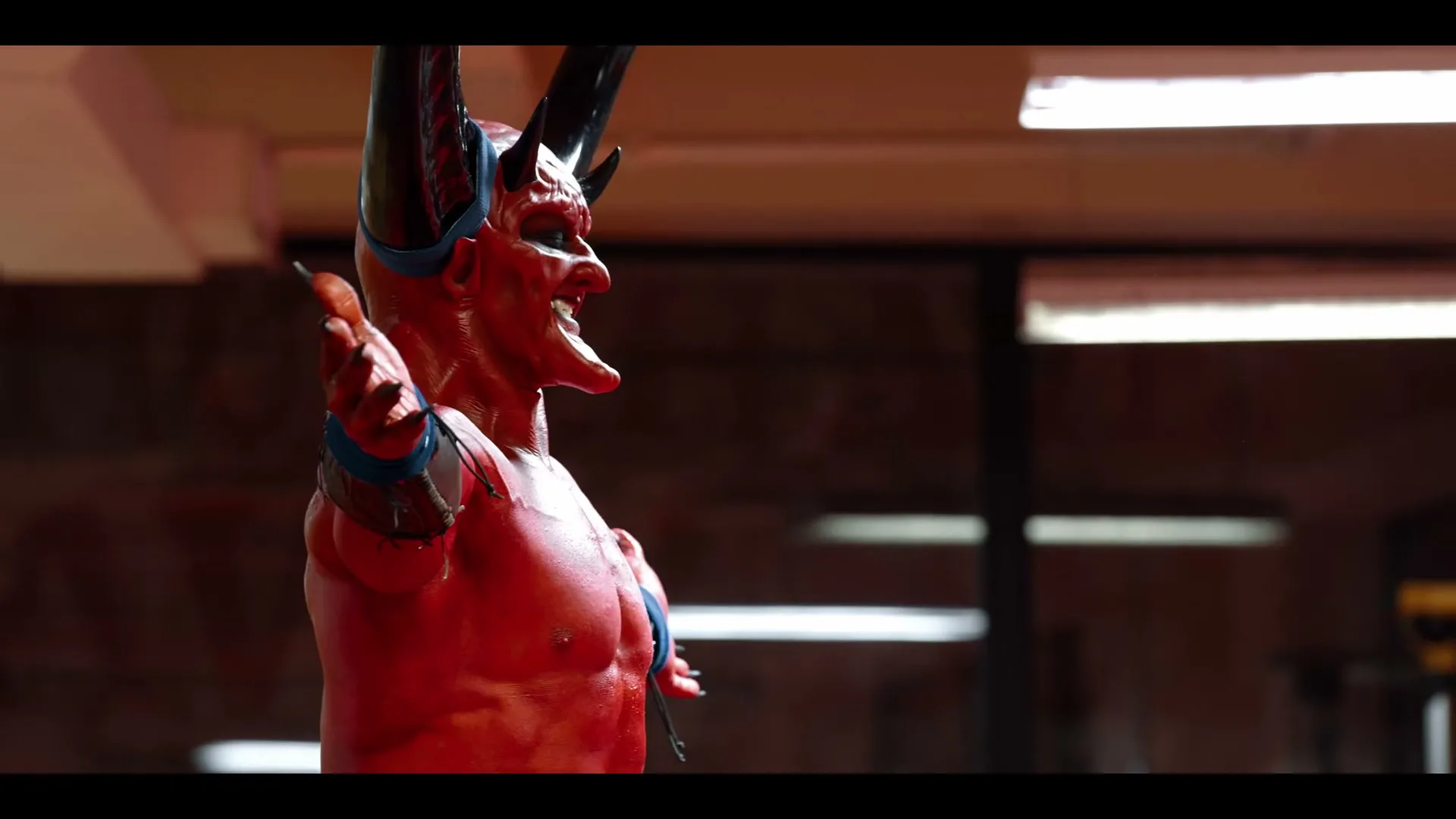 A red devil-like figure with horns and a woman's hand giving a thumbs up are seen in a medium shot, with the devil looking pleased.