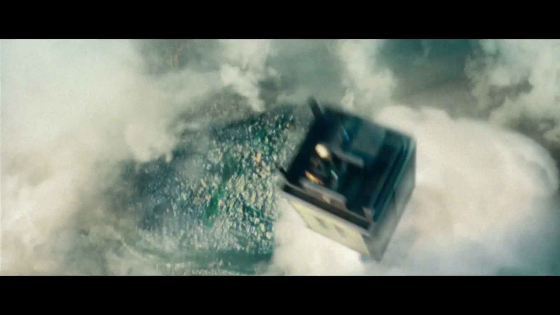 An aerial view shows a city partially obscured by clouds, with a small, box-like structure falling through the sky.
