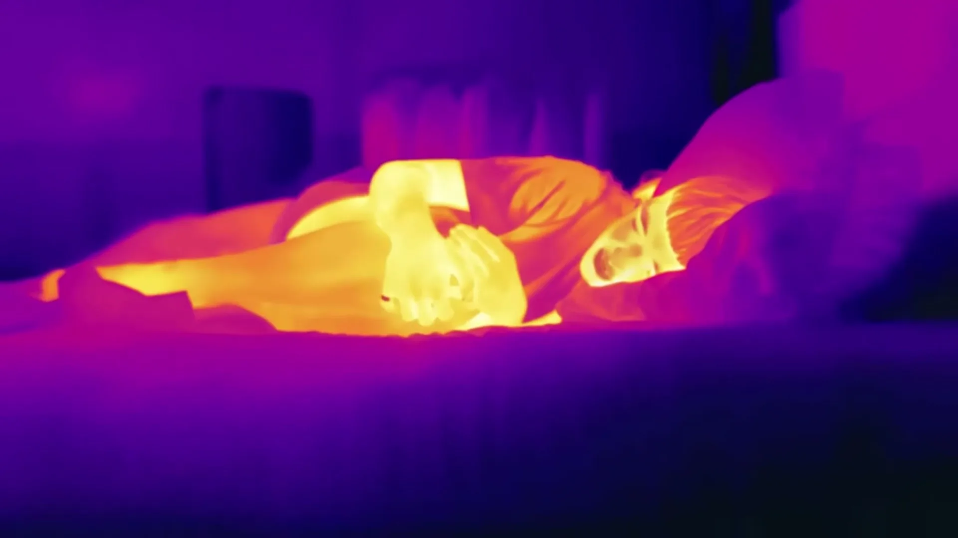 A person in thermal imaging lies awake in bed, tossing and turning, unable to sleep.