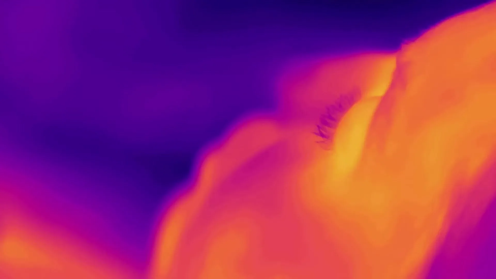 A thermal image of a person's face shows heat radiating from their eye and cheek, with a purple background.