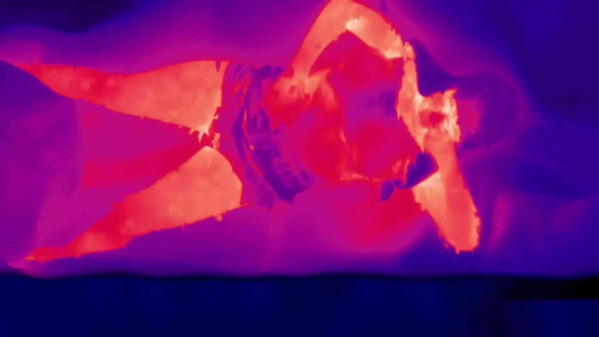 A thermal image of a woman lying on her side in bed, tossing and turning, as her body heat fluctuates and distorts.