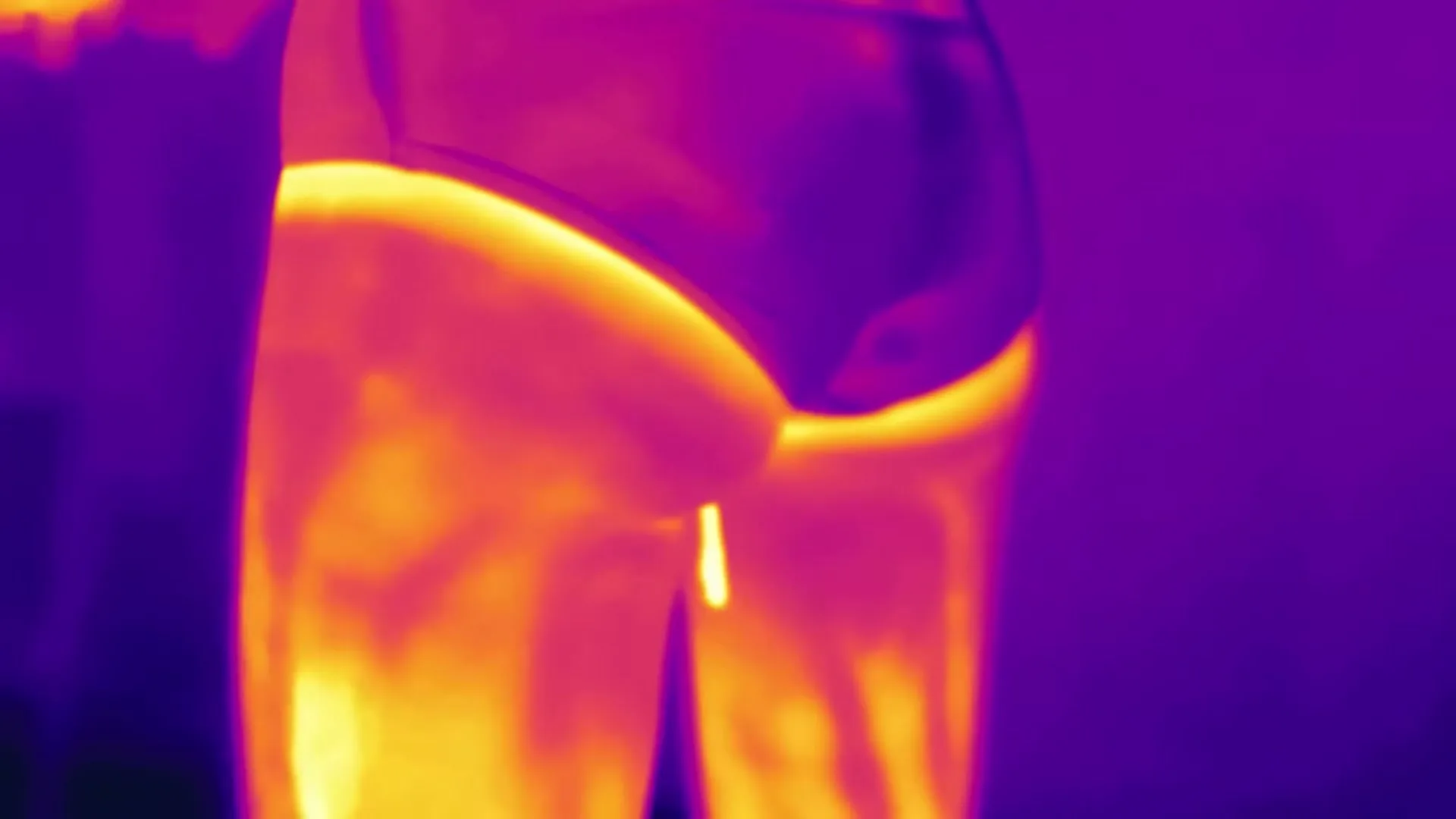 A thermal image of a person's lower body, showing heat patterns in shades of purple, orange, and yellow.