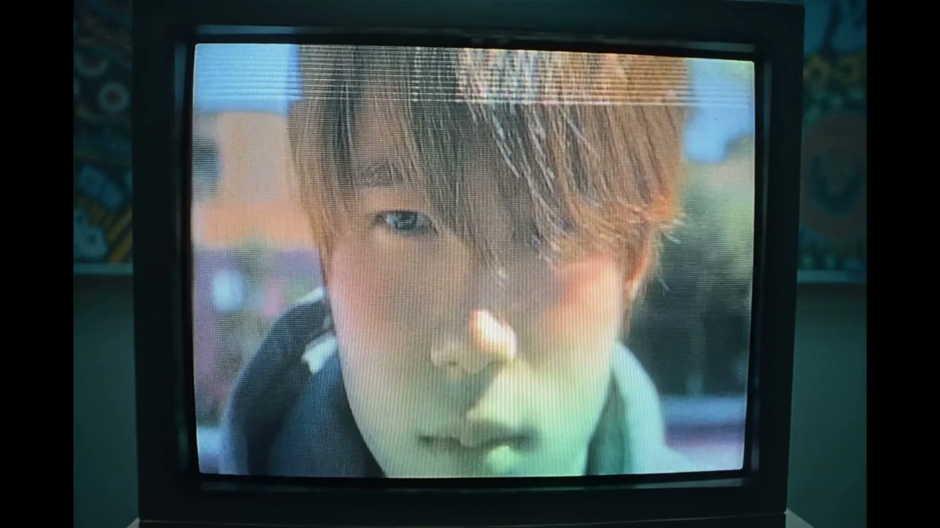 A young person with brown hair and a hoodie opens their eyes, looking directly at the camera, displayed on an old CRT television screen.
