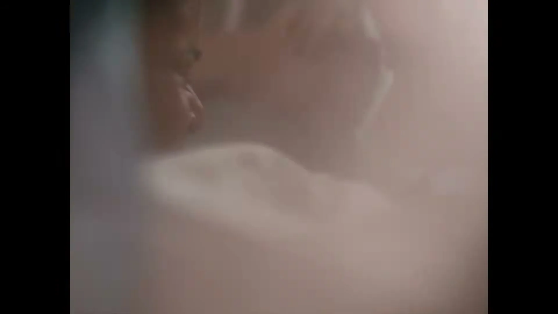 A blurry shot of a person's face and shoulder, possibly in a bed, with soft light filtering in, creating a hazy atmosphere.
