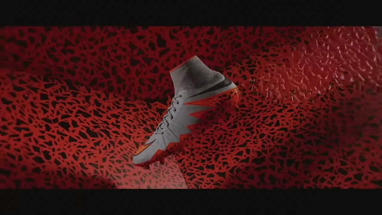A white and orange Nike Hypervenom soccer cleat floats in a dark space as red, textured tendrils grow and envelop it.