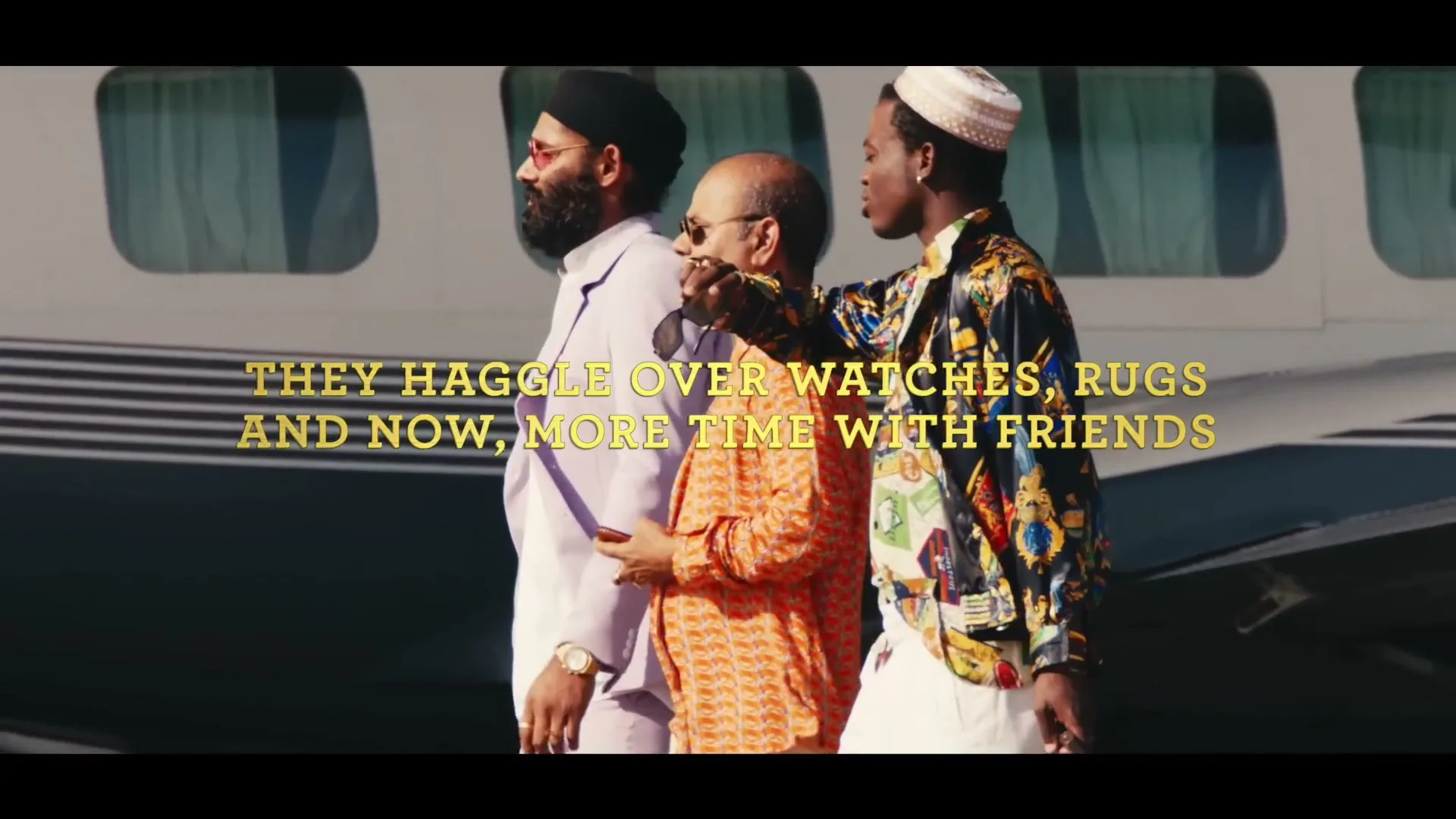 Three men in stylish clothes walk past a private jet on a sunny day, with text overlay about haggling.