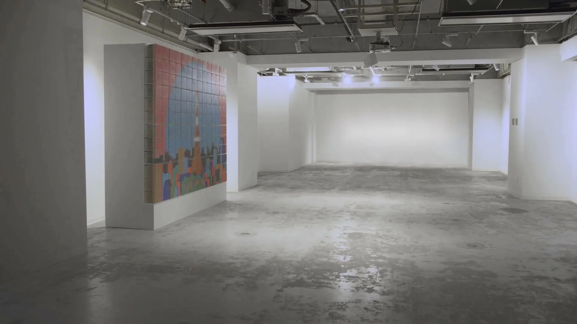 A wide shot of an empty, brightly lit art gallery with a large, colorful pixelated artwork depicting a city skyline on a white pillar.