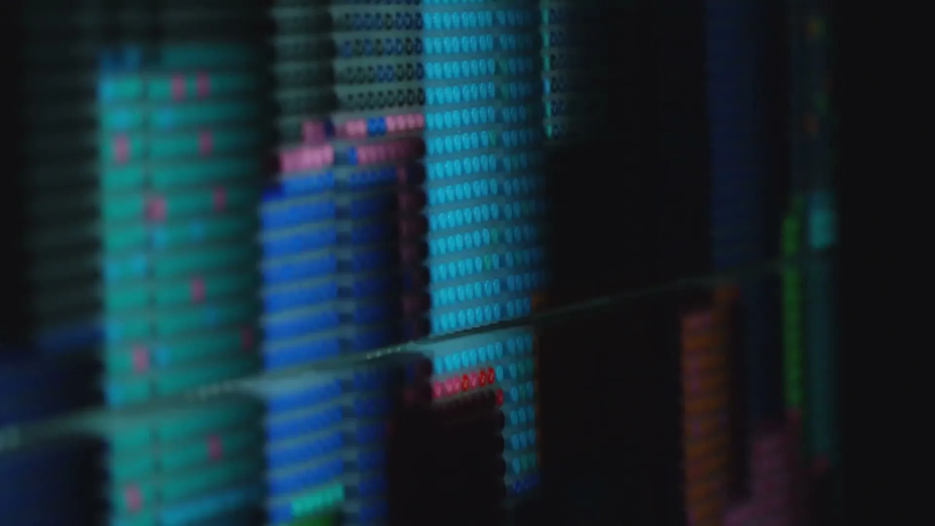 A close-up shot shows a wall of colorful pens, arranged in rows, with a dark silhouette of a person on the right side.