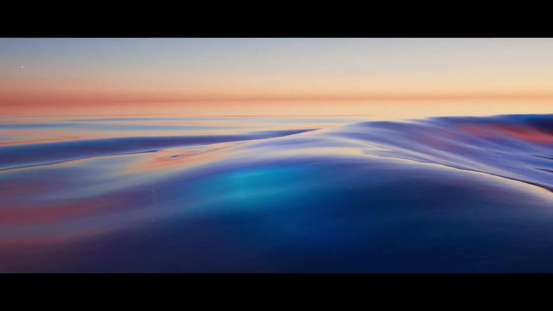 A wide shot of a calm, colorful ocean with a sunset sky, featuring gentle waves reflecting vibrant hues of blue, pink, and orange.