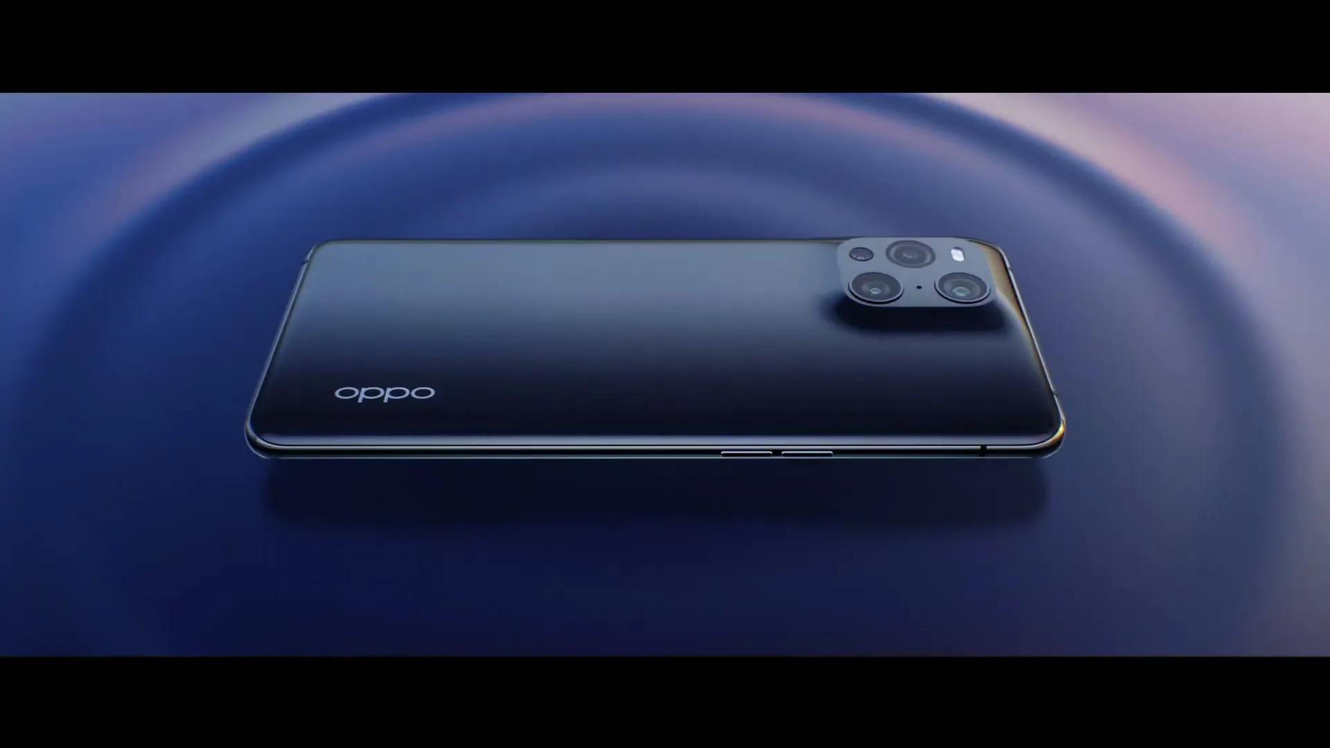 A black OPPO Find X3 smartphone with multiple cameras on its back, rotates slowly on a dark blue, rippled surface in a studio.