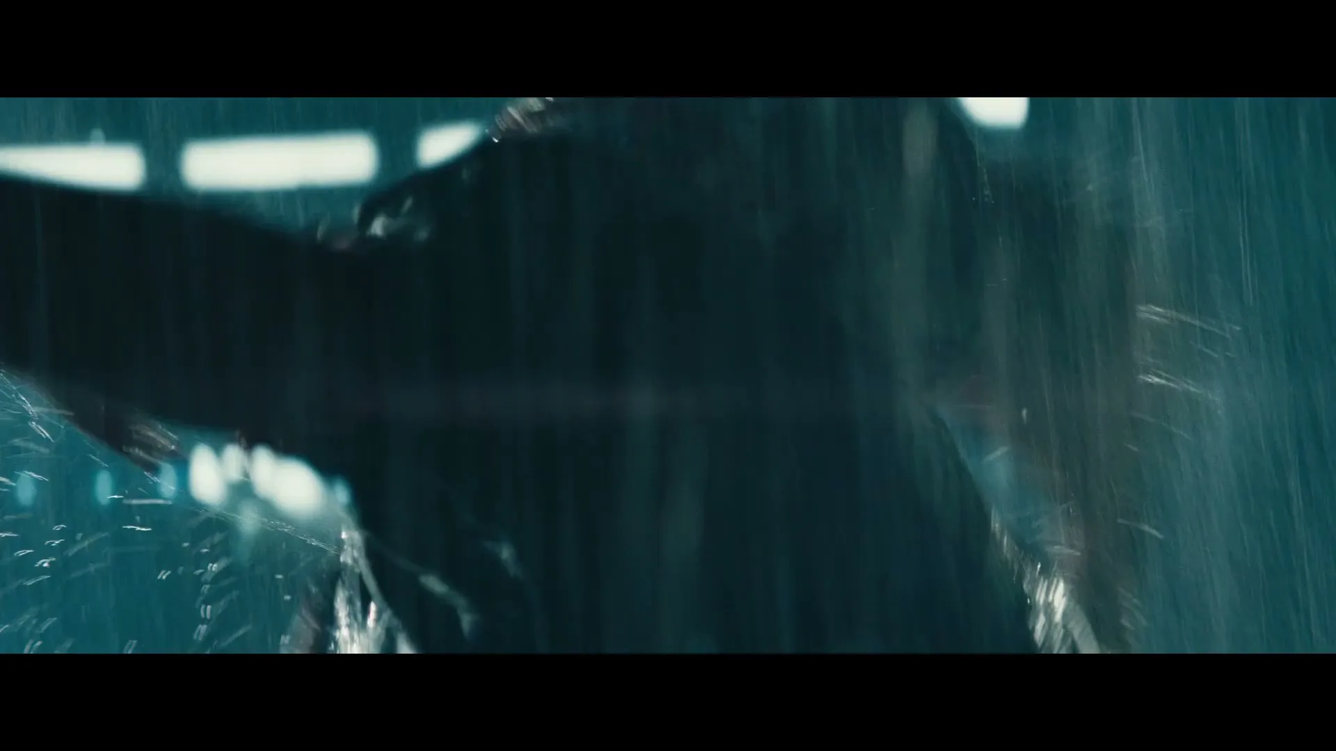 A person in a dark jacket runs through heavy rain at night, with blurry lights in the background.