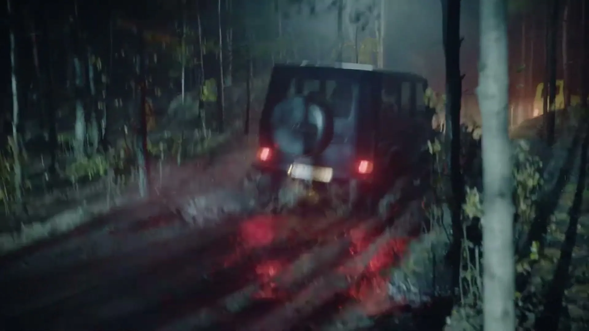 A dark Mercedes-Benz G-Class drives away on a muddy forest road at night, with another vehicle visible in the distance.