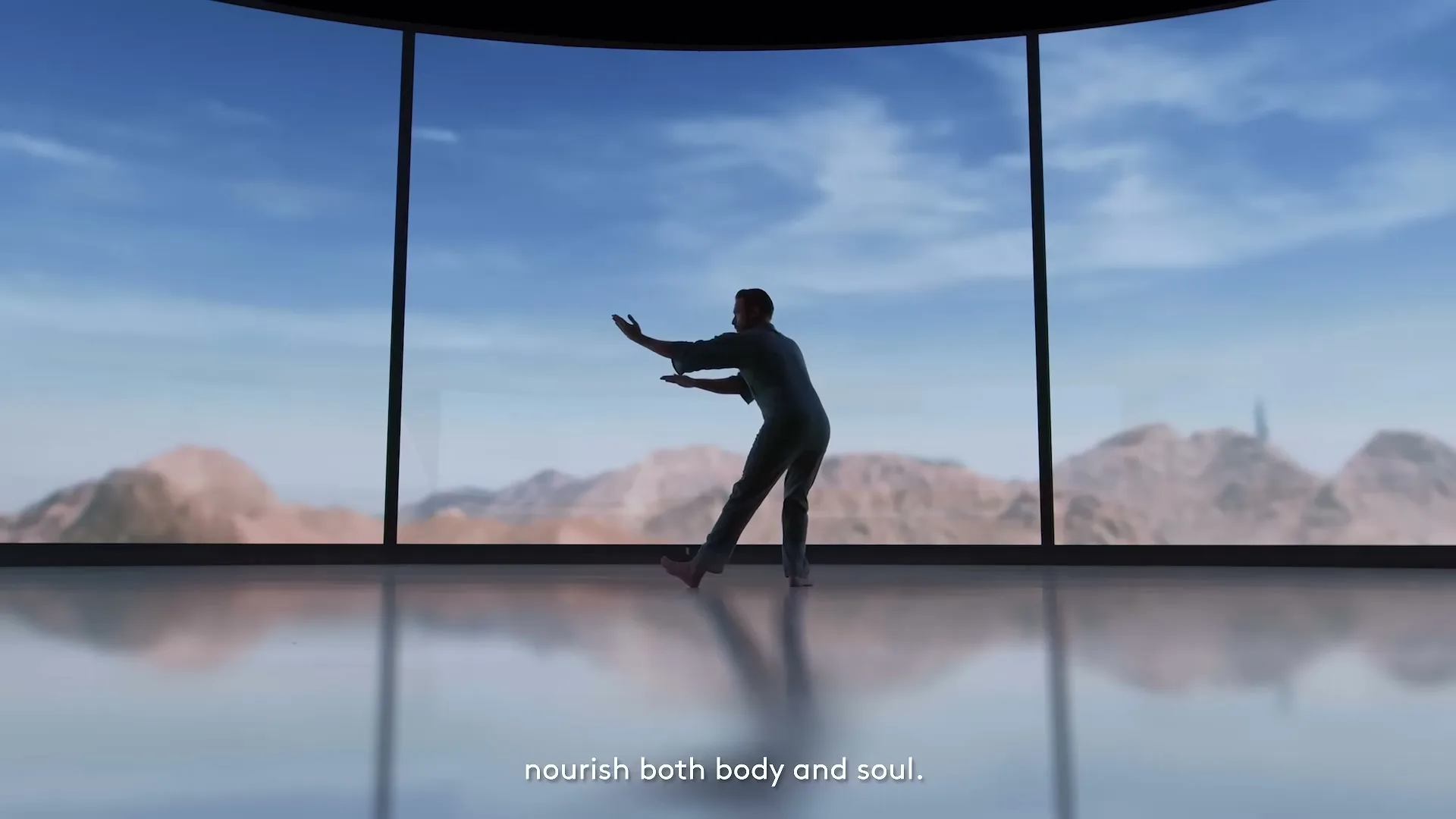 A man in silhouette practices tai chi in a modern, minimalist room with a large curved window overlooking a desert mountain landscape.