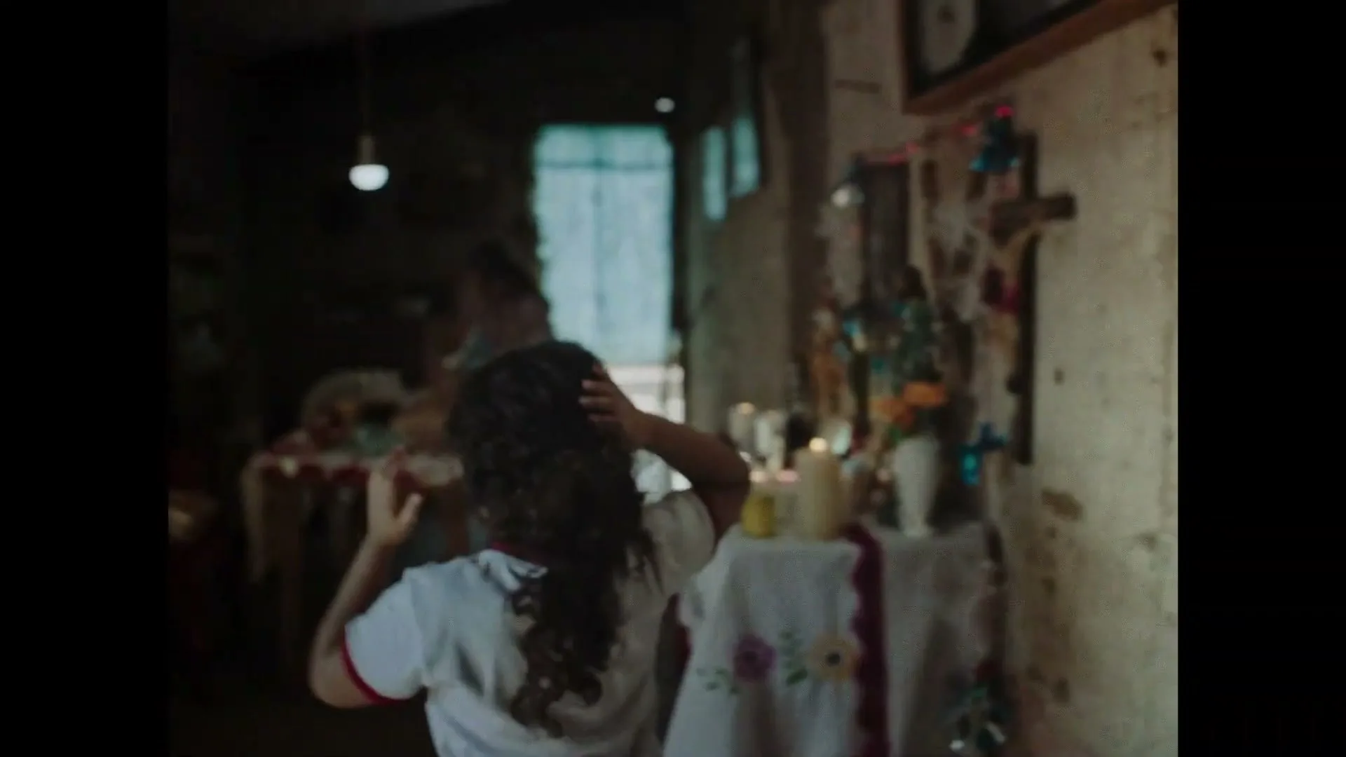 A young girl and her mother are in a dimly lit, rustic home, as the father, a police officer, prepares to leave for work.