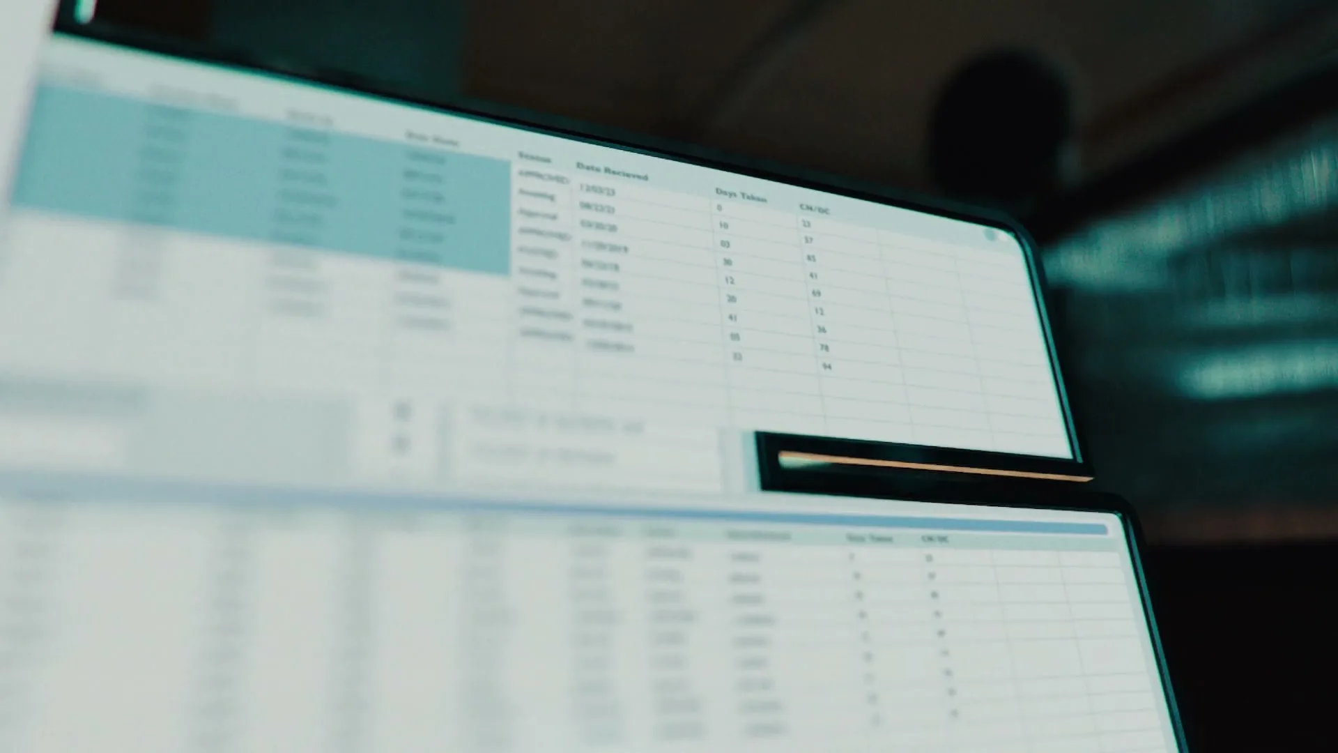 A close-up shot of a computer screen displaying a CRM development interface with data tables, in a dimly lit office.