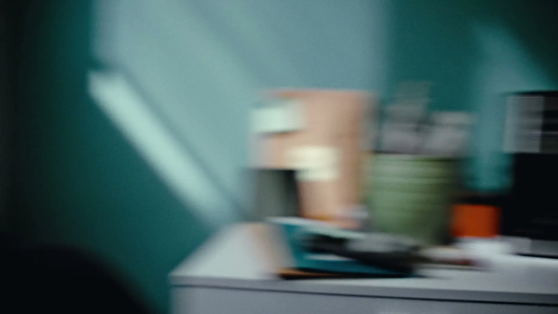 A blurry shot of a home office desk with a computer monitor and various office supplies, as the camera quickly pans right.