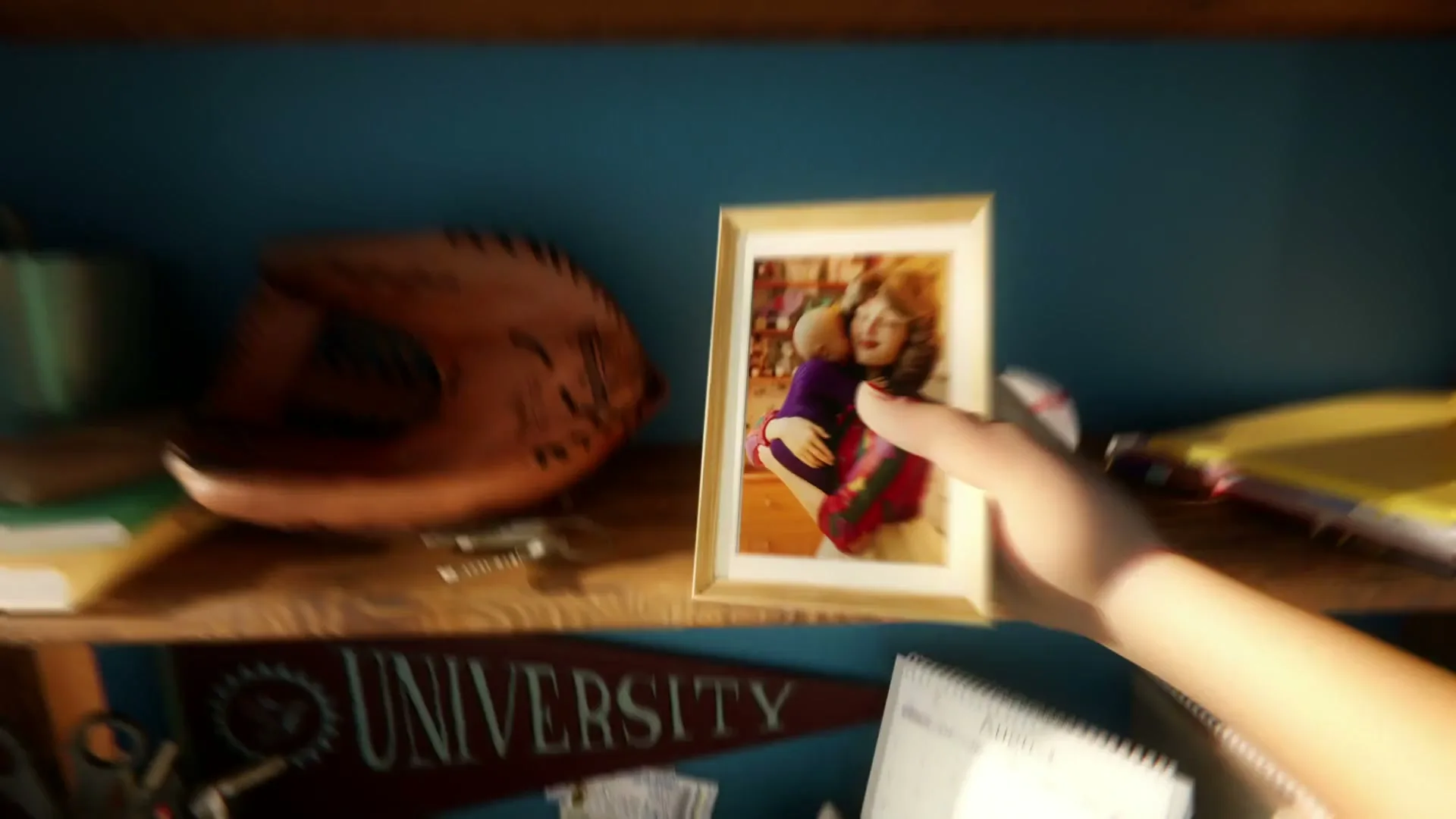 A hand places a framed photo of a woman holding a baby on a wooden shelf, next to a baseball glove and a baseball.