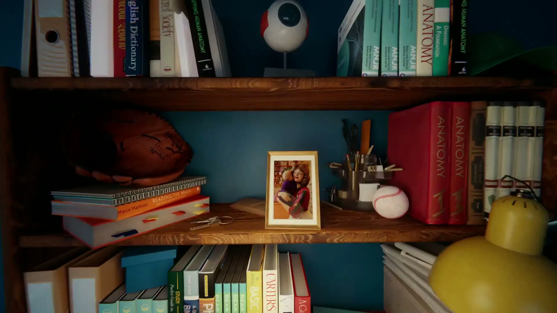 A hand reaches into a bookshelf to grab a baseball, revealing a framed photo of two women, books, and a university pennant.