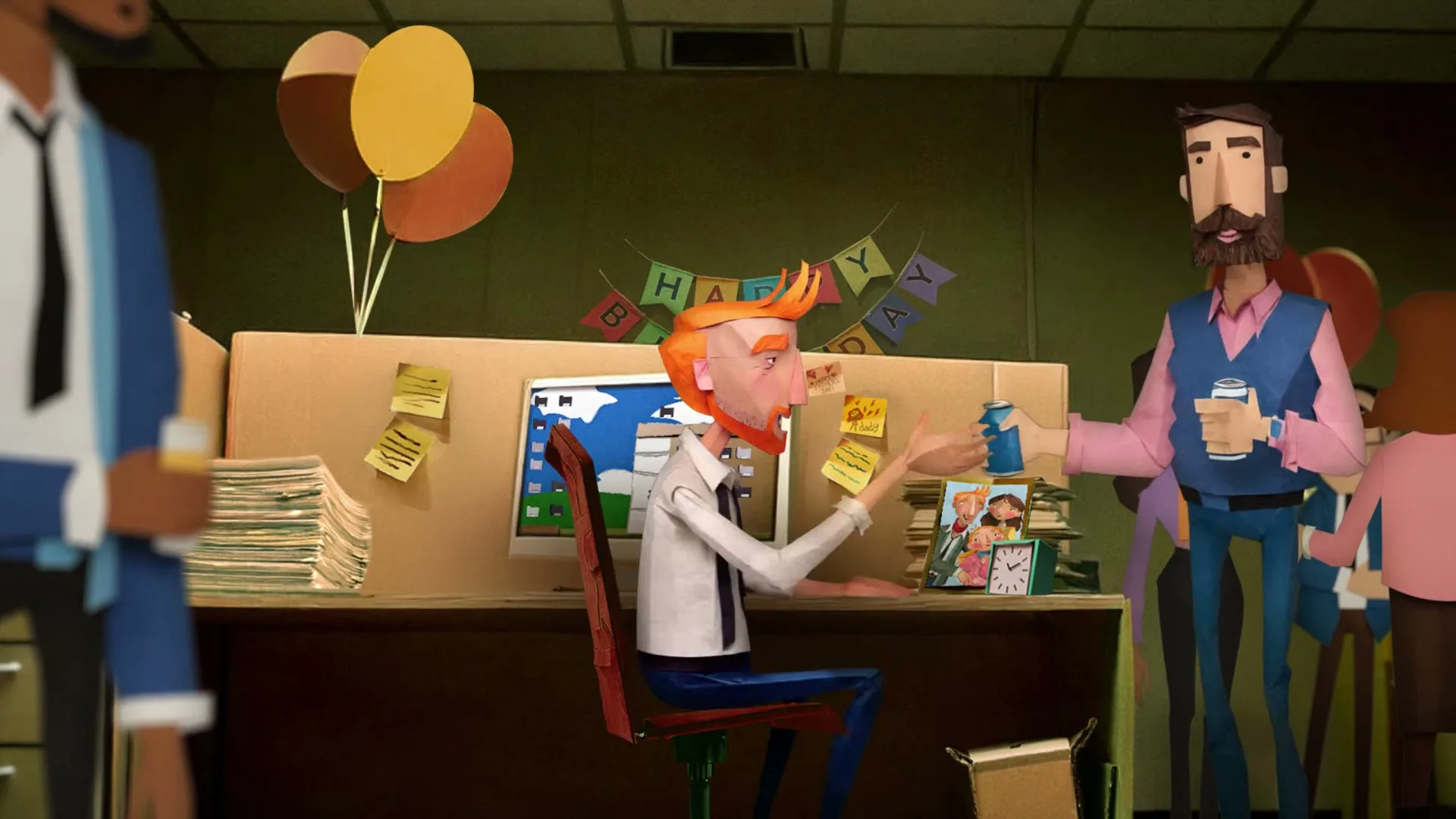 A red-haired man sits at his desk, which is decorated with a "Happy Birthday" banner and balloons, as a bearded man hands him a drink in an office.