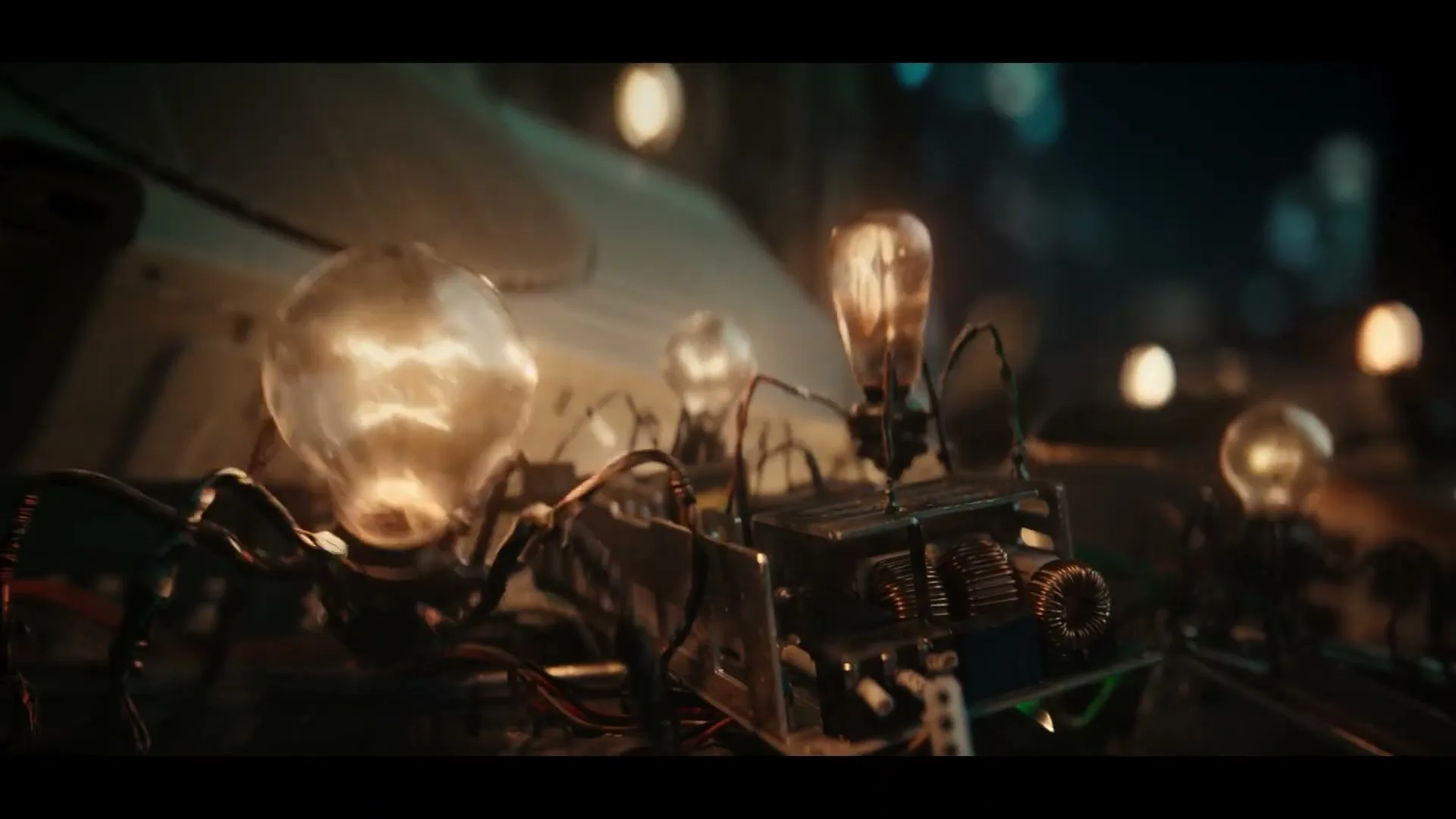 A close-up shot shows a mechanical spider-like creature with a lightbulb for a body, as it is destroyed by an unseen force.